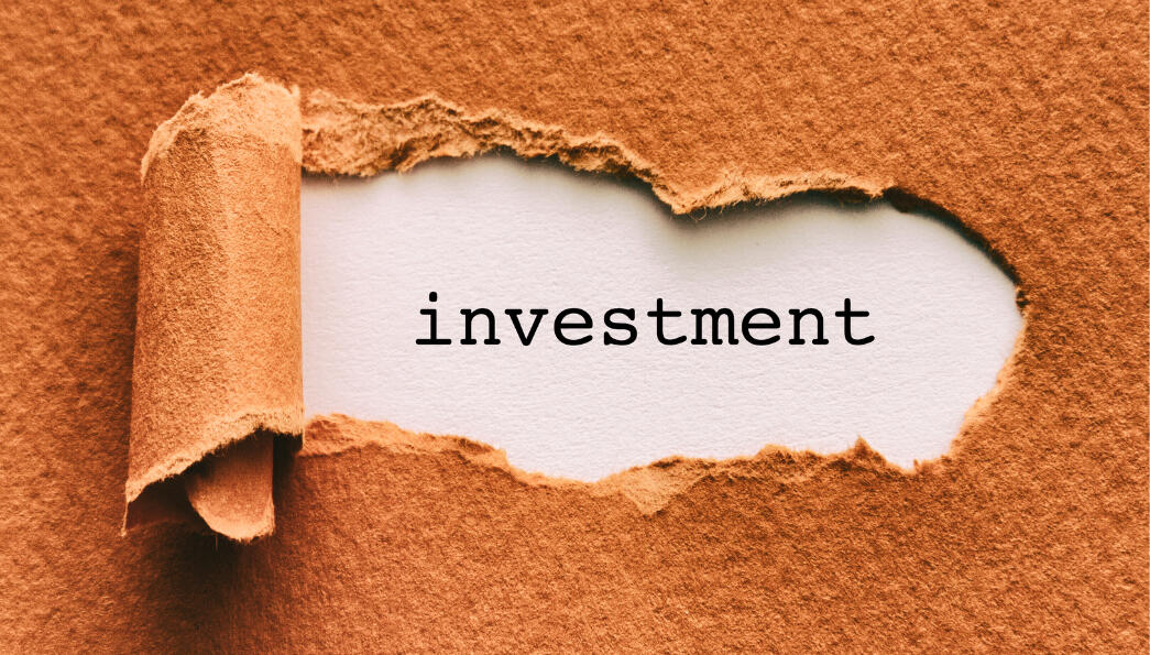 Investment Brown envelope with rip in centre revealing the word investment
